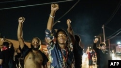 Protesters raise their fists during a demonstration against the shooting of Jacob Blake in Kenosha, Wisconsin on August 26, 2020. - Two people were shot dead and a third injured on the night of August 25 in the US city of Kenosha, Wisconsin.