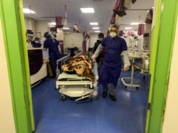 A medic moves a patient in a ward dedicated for people infected with the coronavirus, at Forqani Hospital, in Qom, 78 miles (125 kilometers) south of the capital Tehran, Iran, Feb. 26, 2020.