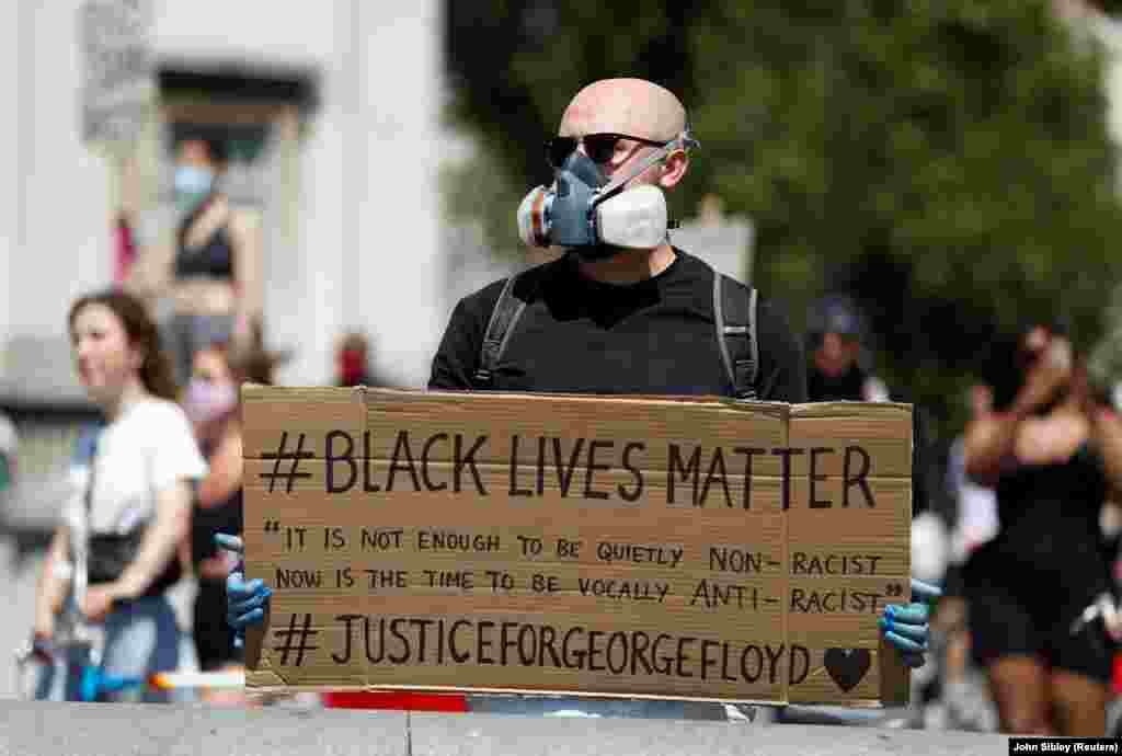 Great Britain, London, A person wearing a protective face mask holds up a Black Live Matters sign during a protest against the death in Minneapolis police custody of African-American man George Floyd Nchini Uingereza mtu akiwa amevaa barakoa amebeba bango linalosema "Maisha ya Watu Weusi Muhimu" wakati wa maandamano dhidi ya vitendo vya polisi wa Minneapolis takati walipomkamata George Floyd.