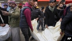 Palestinians carry white sacks containing the bodies of those killed in overnight Israeli airstrikes on the Maghazi refugee camp at Al-Aqsa Hospital in Deir al-Balah, central Gaza Strip, Dec. 28, 2024.
