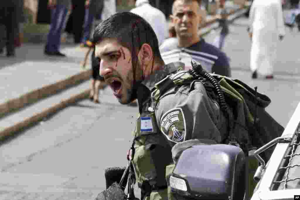 An injured Israeli border policeman reacts during a confrontation with Palestinians after Friday prayers outside the Old City in Jerusalem, Oct. 2, 2015. 