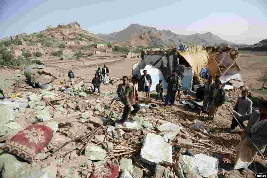 People gather around the wreckage of a house destroyed by an airstrike that killed three women and three children from one family, in the Bait Rejal village, west Sana'a, April 7, 2015.