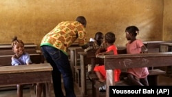 Une agent de santé, au centre, prélève la température des élèves en prévention de la maladie à virus Ebola, Conakry, Guinéé, le 19 janvier 2015. 