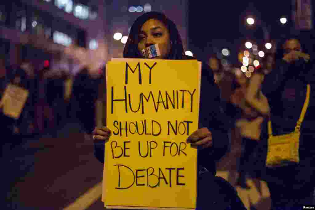 Seorang perempuan di Brooklyn, New York, memegang kertas yang menyerukan keadilan bagi Eric Garner (4/12)