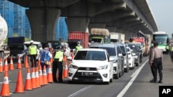 Para petugas kepolisian mengecek mobil-mobil di jalan tol Cikarang, Jawa Barat, untuk mencegah warga agar tidak pulang kampung di tengah pandemi virus corona, 24 April 2020.