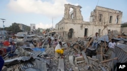 Warga setempat berjalan melalui bangunan yang hancur menyusul dua serangan bom mobil di ibukota Mogadishu, Somalia, Sabtu, 24 Februari 2018. 
