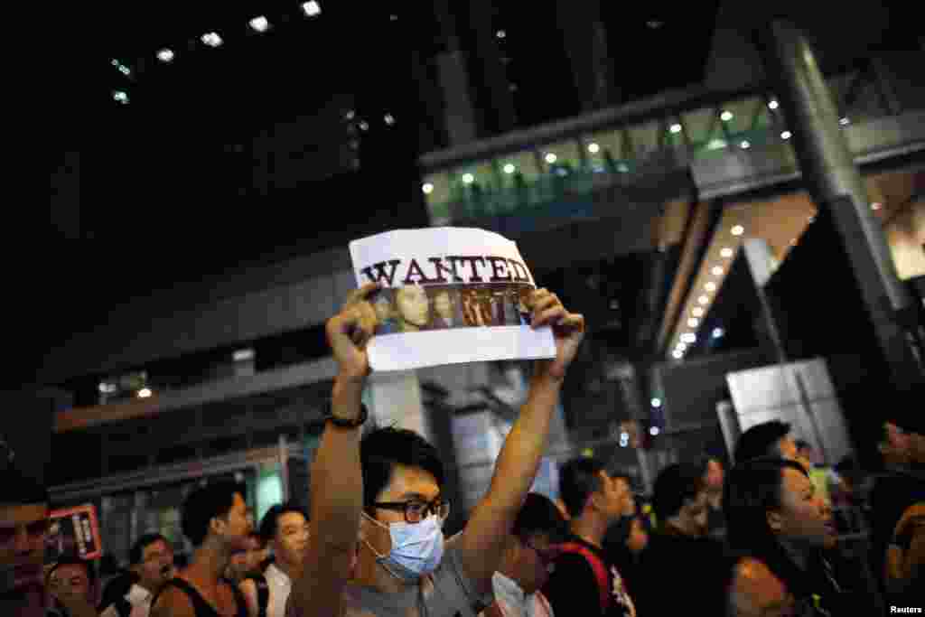 Seorang demonstran pro-demokrasi memegang gambar-gambar polisi yang diduga memukuli demontran di distrik Wan Chai di Hong Kong (14/10). (Reuters/Carlos Barria) 