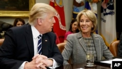 FILE - In this Feb. 14, 2017 file photo, President Donald Trump talks to Education Secretary Betsy DeVos in the Roosevelt Room of the White House in Washington. A new study published Tuesday has found increased support for charter schools and private school voucher programs. The study suggests that Republican Party support for these programs had a strong influence on the increase. (AP Photo/Evan Vucci, File)