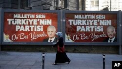 Seorang perempuan berjalan melewati poster PM Turki Binali Yildirim dalam rangka memperingati ulang tahun ke-15 partai AKP di Istanbul (15/8).