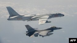 Sebuah jet tempur F-16 Taiwan terbang di sebelah pesawat pengebom H-6 China, atas, di wilayah udara Taiwan, dalam foto yang diambil dan dirilis pada 10 Februari 2020. (Foto: AFP)