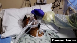 Medicinska sestra Alma Abad dodiruje glavu pacijenta oboljelog od koronavirusa, na odjeljenju Intenzivne njege u bolnici Roseland, u južnom delu Chicaga,, Illinois.