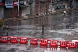 Indian security force personnel stand guard in a deserted street during restrictions after the government scrapped special status for Kashmir, in Srinagar Aug. 8, 2019.