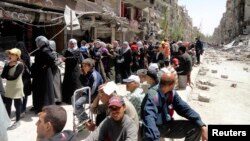 FILE - Residents wait to receive food aid distributed by the U.N. refugee agency at the Palestinian refugee camp of Yarmouk, south of Damascus, Syria, May 2014.
