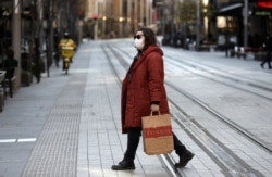 Seorang wanita melintasi jalan yang biasanya sibuk di Sydney, Rabu, 7 Juli 2021. (AP)