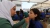 Siswa-siswa pengungsi di salah satu sekolah yang didanai UNRWA di dekat kamp pengungsi Al Wehdat, Amman, Yordania, tengah digambar wajahnya saat menghadiri upacara yang menandai dimulainya tahun ajaran baru, Minggu, 2 September 2018.