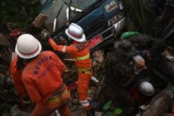 Rescue workers attempt to free a cow caught under a van after a landslide in Paung township, Mon state, Aug. 10, 2019.