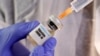  A woman holds a small bottle labbeled with a "Vaccine COVID-19" sticker and a medical syringe in this illustration taken April 10, 2020. REUTERS/Dado Ruvic/Illustration 