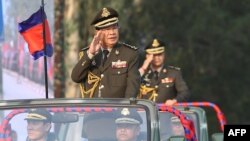 FILE - Cambodian Prime Minister Hun Sen (L) salutes, along with his son, Lt. Gen. Hun Manet (background), during an inspection of troops at a ceremony in Phnom Penh, Cambodia, Jan. 24, 2019. (Handout via AFP)