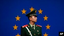 Seorang polisi China berjaga di depan bendera Uni Eropa di kantor delegasi Uni Eropa di Beijing, China (Foto: dok).