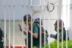 Wartawan Jepang Yuki Kitazumi mengangkat tangannya saat ia dikawal oleh polisi setibanya di kantor polisi Myaynigone di kota Sanchaung di Yangon, Myanmar, 26 Februari 2021. (Foto: AP)
