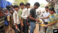 An Indian teacher serves the mid-day meal to children at a Government High School in Hyderabad, January 10, 2012. 