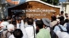 Journalists try to interview a leader of Cambodian activists during a march in front of the Anti-Corruption Unit, in Phnom Penh, Cambodia, Thursday, May 29, 2014. (AP Photo/Heng Sinith)