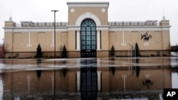 FILE - Rain drops fall on a puddle in an empty parking lot outside a Lord & Taylor store, closed due to the coronavirus outbreak, in Salem, New Hampshire, April 3, 2020. 