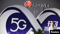 Seorang perempuan berdiri di depan stan Huawei yang memamerkan teknologi 5G di PT Expo, di Beijing, China, 28 September 2018. 