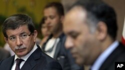 Turkish Foreign Minister Ahmet Davutoglu, left, speaks to Vice-Chairman of the Executive Board of the Libyan National Transitional Congress Ali al-Issawi, right, during a news conference after their meeting in the rebel-held Benghazi, Libya, Sunday, July