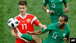 Russia's Roman Zobnin, left, and Saudi Arabia's Abdullah Otayf vie for the ball during the group A match between Russia and Saudi Arabia.
