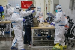 Medical workers in protective suits receive a patient at the Wuhan International Conference and Exhibition Center, which has been converted into a makeshift hospital, to receive patients with symptoms of the coronavirus, in Wuhan, China Feb. 5, 2020.