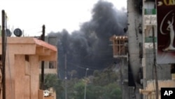 Libyan rebels are seen walking down a street close to a building where forces loyal to Col. Moammer Gadhafi are reportedly held up in the Zwabi district of Misrata on April 24, 2011