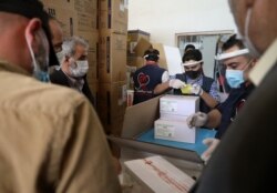FILE - Staff of the Physicians Across Continents group unload the first batch of AstraZeneca COVID-19 vaccines at Bab al-Hawa border crossing between Syria and Turkey in Syria's rebel-held northwestern Idlib, April 21, 2021.