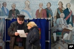 Masyarakat memeriksa surat suara di TPS yang terletak di sebuah sekolah saat pemilihan presiden di St. Petersburg, Rusia, Sabtu, 16 Maret 2024, (Foto: AP)