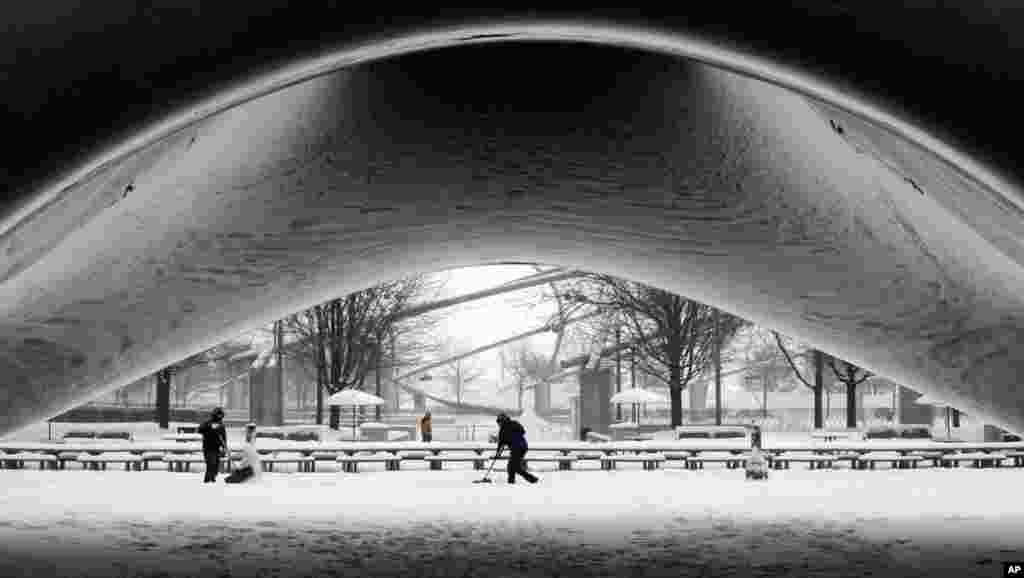 A park crew clears the snow around Annish Kapoor&#39;s stainless steel Cloud Gate sculpture in Millennium Park, Chicago, Jan. 2, 2014.
