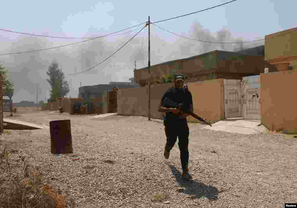 A fighter of the Asaib Ahl al-Haq Shi&#39;ite militia takes cover from sniper fire, Sulaiman Bek, Sept. 1, 2014.